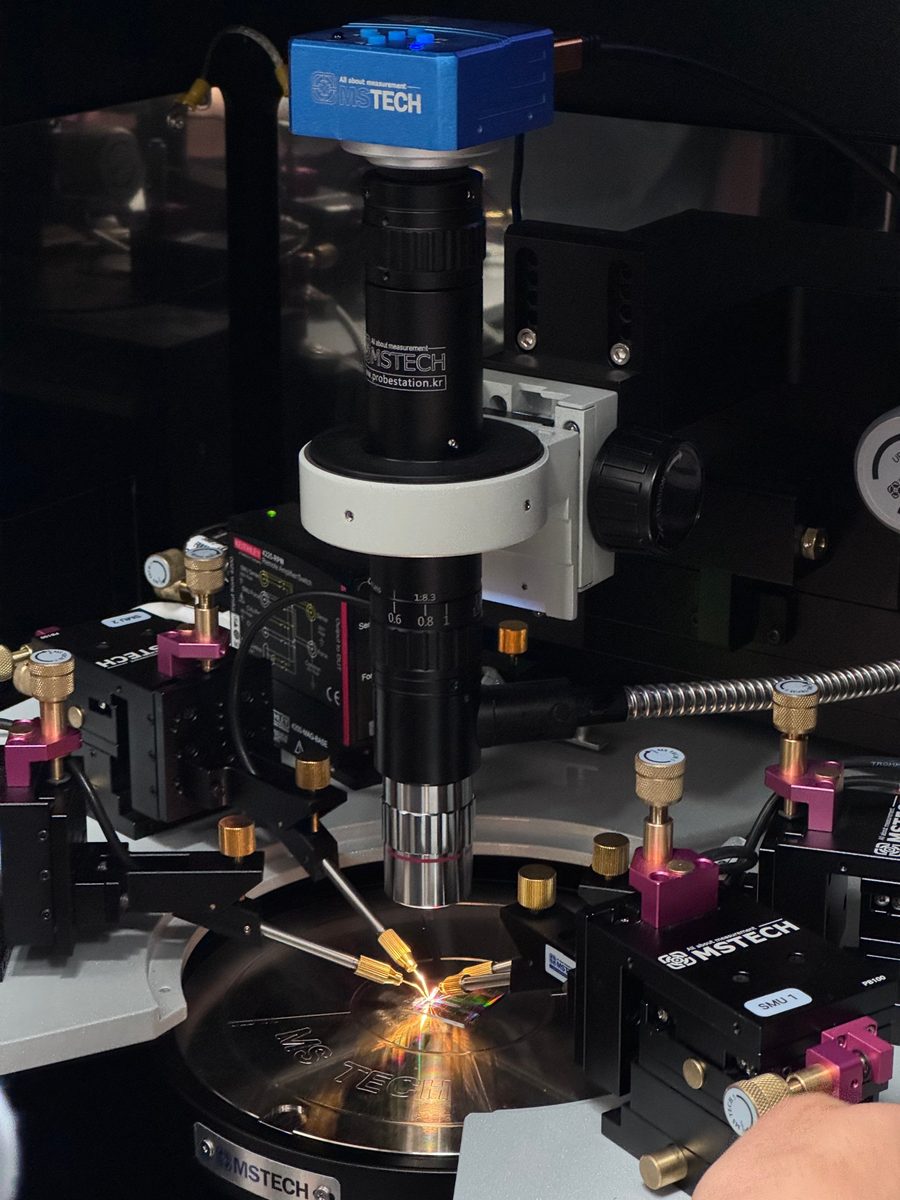Probe station with four micro-positioner probes landing on a die under a microscope